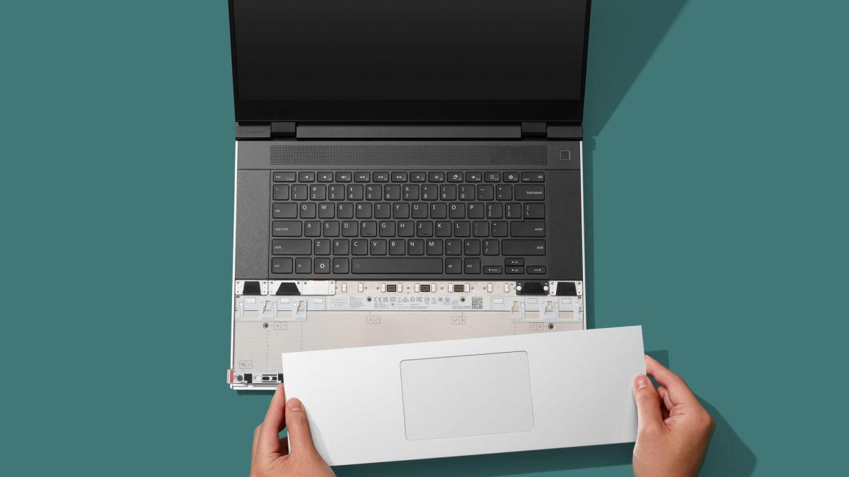 Framework Laptop 16 sits against a turquoise background. A pair of hands clicks the new one-piece haptic touchpad into place.