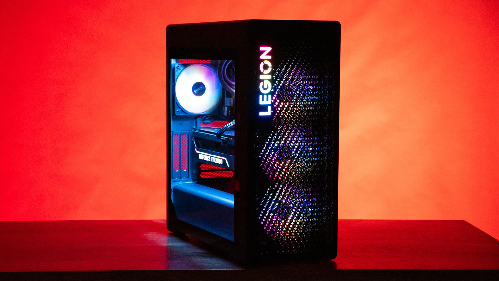 Um computador desktop em uma mesa com iluminação LED e fundo vermelho.