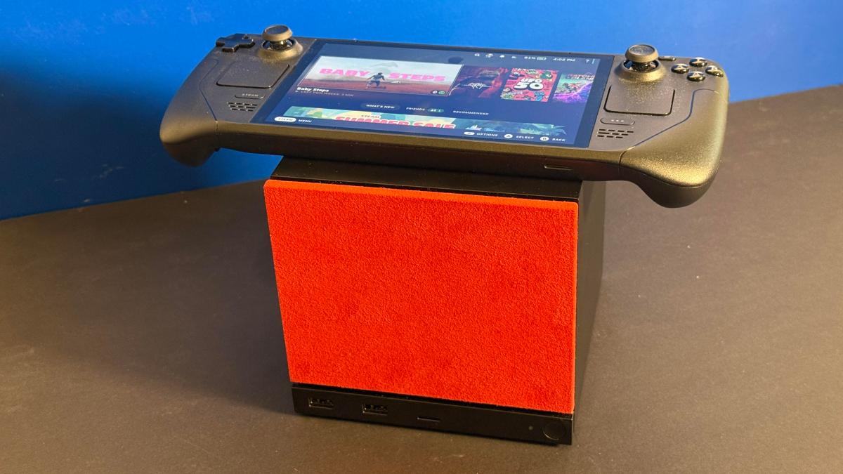 Steam Deck posicionado em cima do Steam Machine com placa frontal vermelha